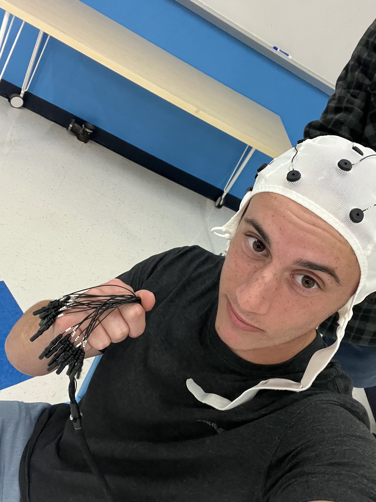 David wearing an EEG cap and holding its electrode leads