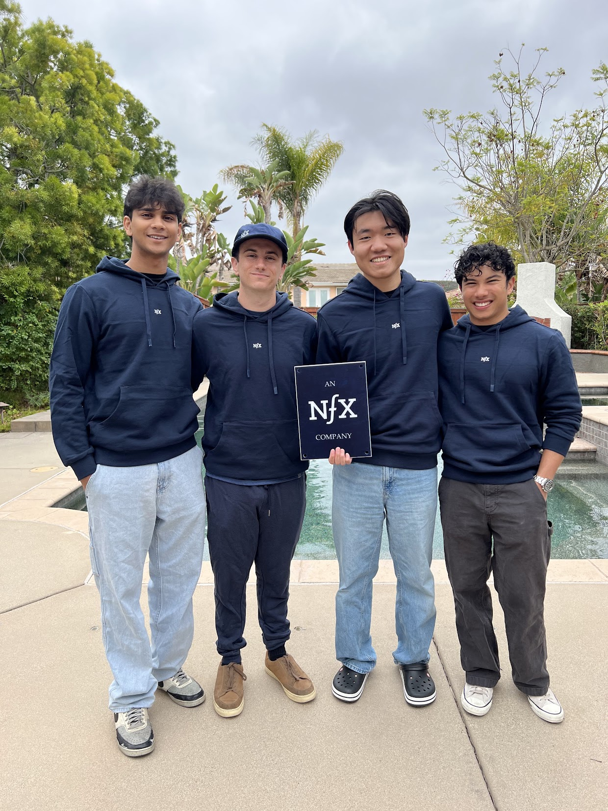The founding team in NFX hoodies holding an “An NFX Company” plaque after the pre-seed raise