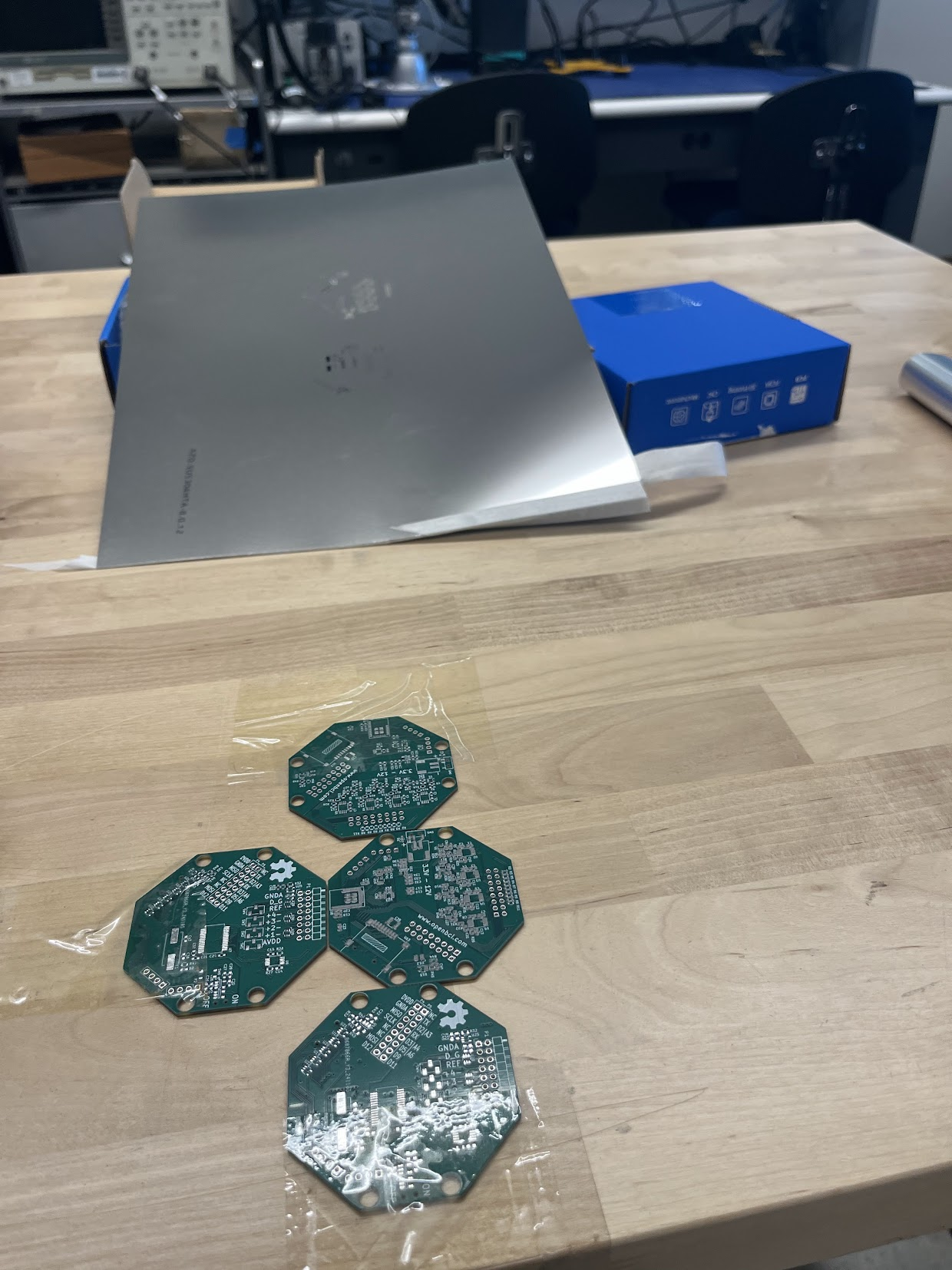 Octagonal green PCBs with solder mask beside a solder-paste stencil